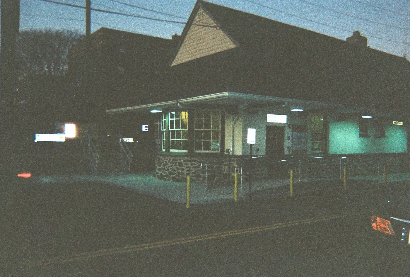 The Woodmere Long Island Rail Road station at dusk, lit from inside.